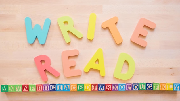 Words READ and WRITE from multicolor wooden letters on wooden table.