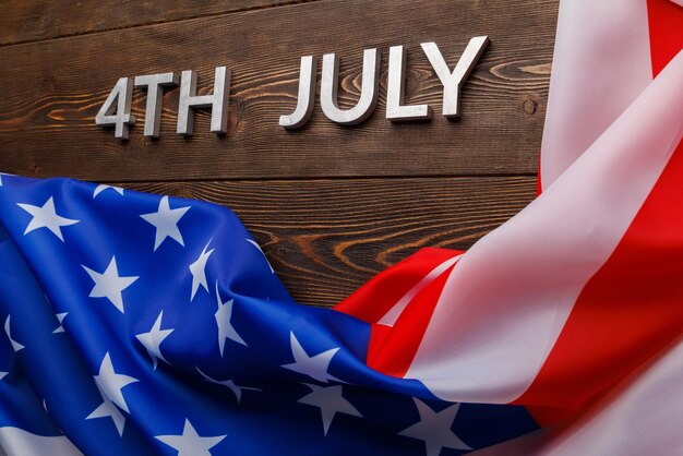 The words th july and crumpled usa flag on flat textured wooden surface background