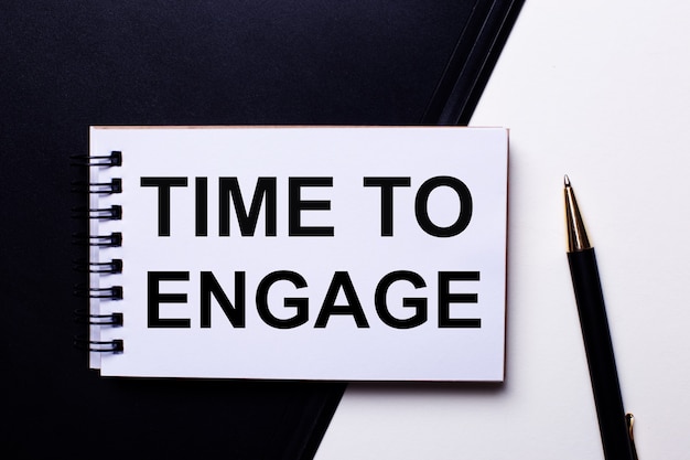 The words TIME TO ENGAGE written in red on a black and white background near the pen