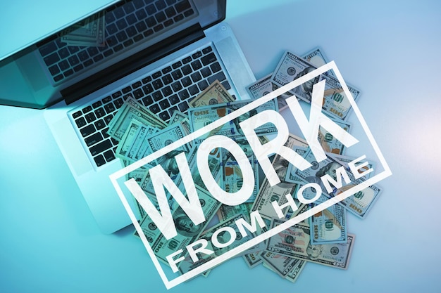 Photo words work from home on a cloused silver laptop and dollars cash night online in the color light on