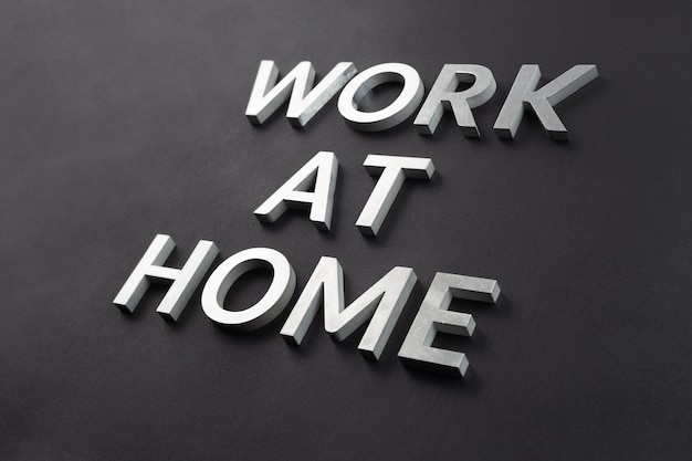 The words work at home laid with silver metal letters on matte black background in diagonal