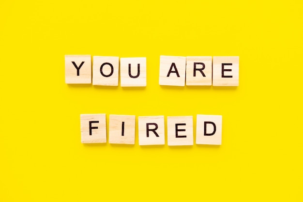 words You Are Fired. Wooden blocks with lettering on top of yellow table. Human Resource Management and Recruitment and Hiring concept