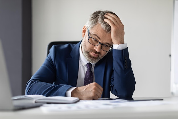 Work Burnout Portrait Of Upset Mature Businessman Sitting At Desk In Office