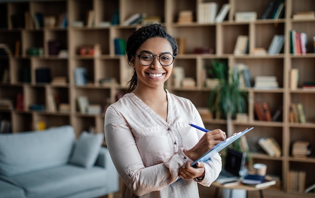 Work and business Glad smiling millennial black woman psychologist in glasses with tablet look at camera