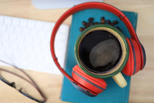 The work desk has a coffee cup and red headphones and office supplies 