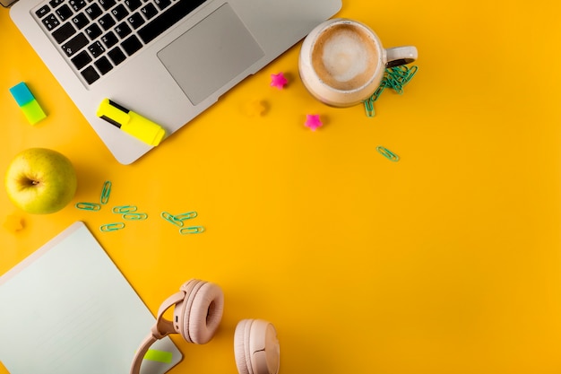 Work desk top view laptop and stationery on yellow background home schooling concept