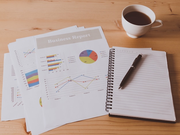 Photo work desk with bussiness chart  and spectacles on wooden desk.