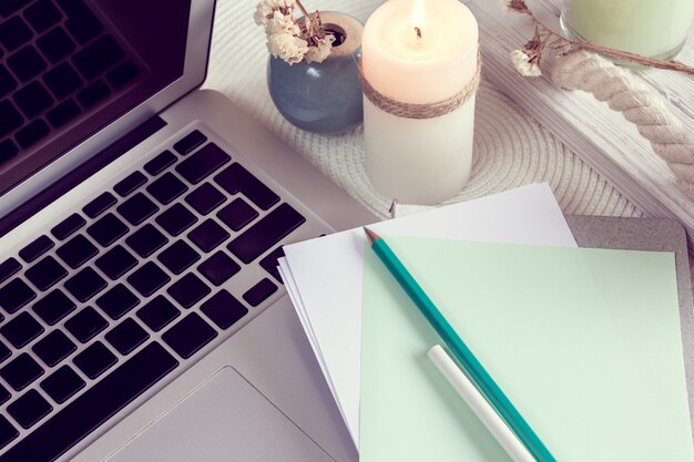 Work desk with notebook, laptop and candle