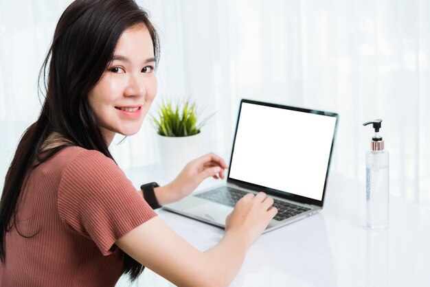 Работа на дому, видеоконференцсвязь с молодой азиатской бизнес-леди или онлайн-встреча в режиме реального времени на переднем портативном компьютере изолирует болезнь коронавирус или COVID-19 в домашнем офисе