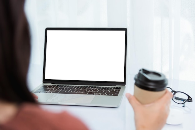 집에서 일하고, 아시아 젊은 여성 사업가 화상 회의 통화나 페이스타임 온라인 회의에서 전면 노트북 컴퓨터에 있는 커피 컵을 들고 홈 오피스에서 질병 코로나바이러스나 COVID-19를 격리합니다.