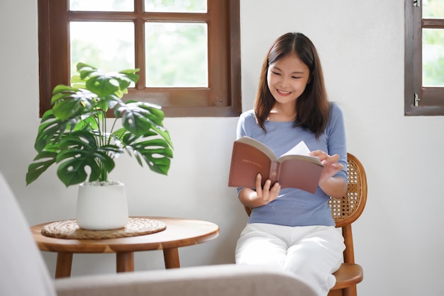 Work from home concept Business women is sit beside the window to relaxing with reads a book