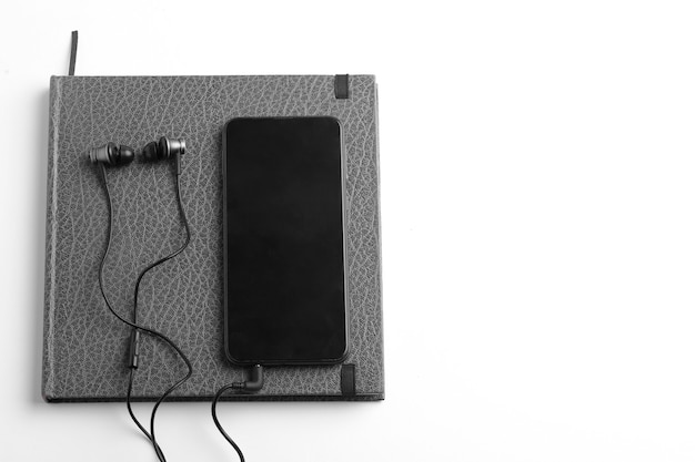 Work from home concept. smartphone, diary and earphone on white surface