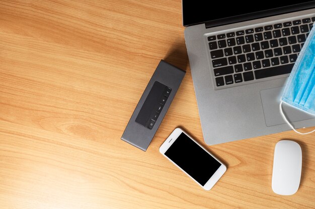 Photo work from home concept. top view laptop, mouse, smartphone, speaker and face mask on wood table .