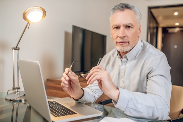 Work from home. Gray-haired man working from home and looking busy