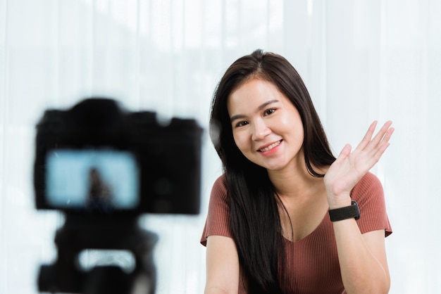 Работа из дома. Улыбающаяся счастливая азиатская молодая красивая женщина-блогер с профессиональным цифровым технологическим оборудованием, запись в прямом эфире, видеозвонок, видеоконференция, онлайн-канал видеоблога