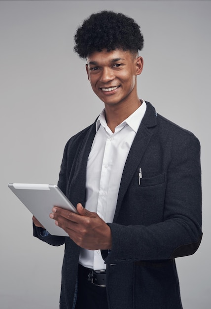 Work hard keep it smart Studio shot of a young businessman using a digital tablet against a grey background