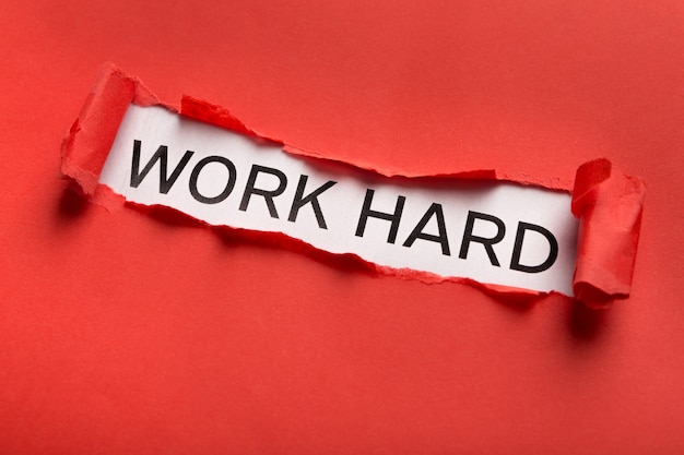 Work hard motivational inscription behind ripped red paper. Inspiration and support concept, quote for banner, poster or clothing design, copy space