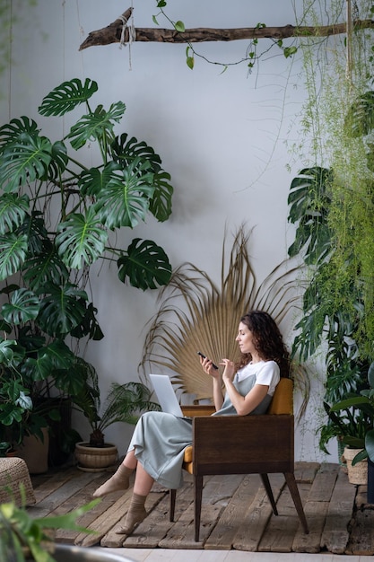 Work at home office in indoor garden young freelance woman work on use and smartphone in greenhouse