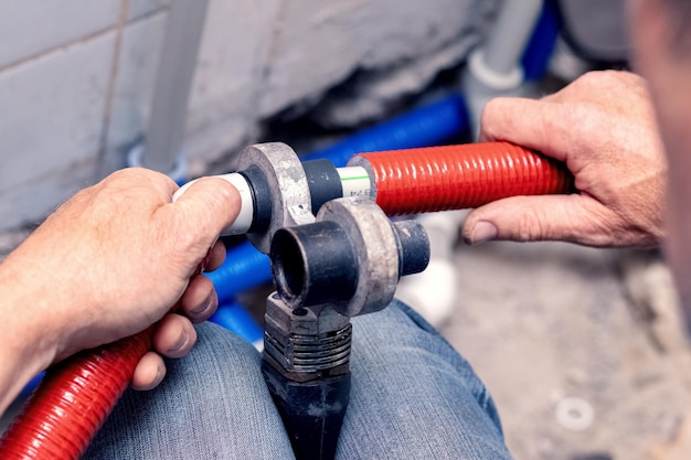 Lavori sull'installazione di riscaldamento o impianto idraulico il master collega i tubi di plastica con un saldatore