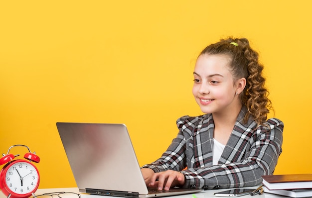 Photo work on laptop. schoolgirl has online homework. back to school. time to study. small girl in office. little businesswoman. happy childhood. kid with curly hair wear jacket.