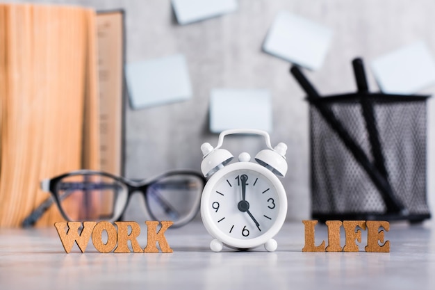 Концепция баланса трудовой жизни Деревянные буквы и будильник на рабочем столе