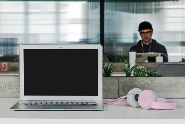 Work on a notebook in a modern office. The notebook stands at the back of the table which grows indoor plants and man works