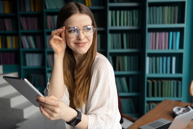 Work a smart woman with glasses uses a tablet workplace in a new office