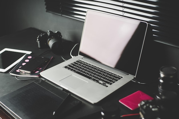 Work space on black table of a photographer or designer with laptop retro camera Stylish home studio concept of hipster Seleted focus