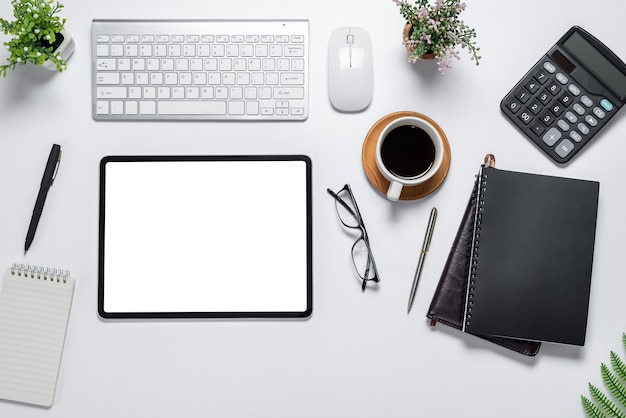 Su uno spazio bianco sul tavolo da lavoro e su uno schermo bianco tablet con attrezzatura da lavoro.