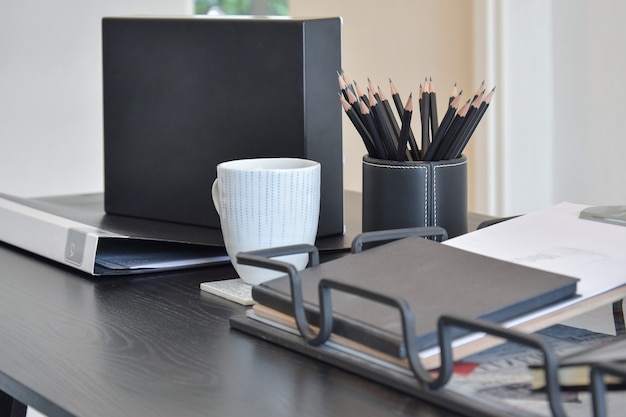 Foto tavolo da lavoro con libro, matite, tazza di caffè e orologio in una casa