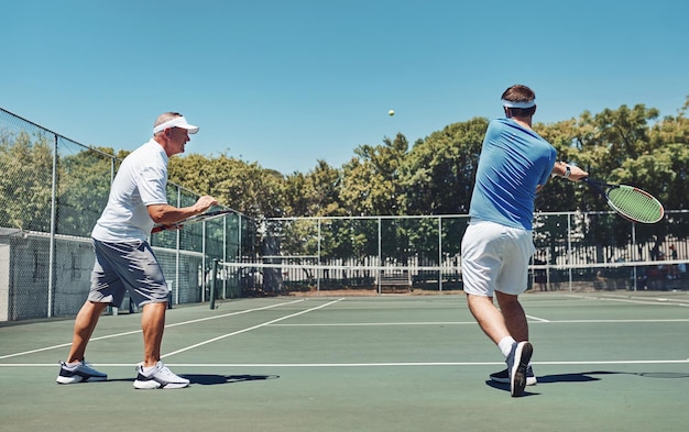 Work on that swing Full length shot of a handsome mature sportsman coaching a fellow teammate during a tennis training session