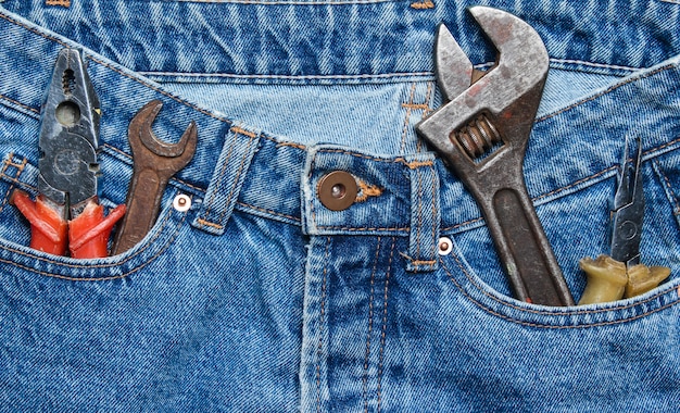 Work tool in the pocket of blue jeans. pliers, wrench, adjustable wrench