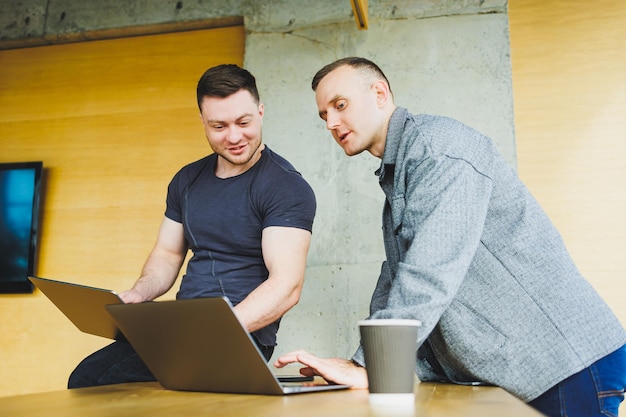 Work of two colleagues sitting together while exchanging ideas with a laptop in a meeting room and analyzing work charts Work in a modern spacious office