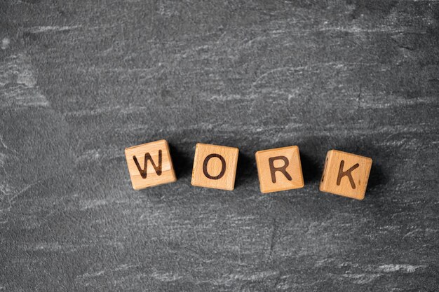 Photo work word is made of wooden blocks lying on the dark background