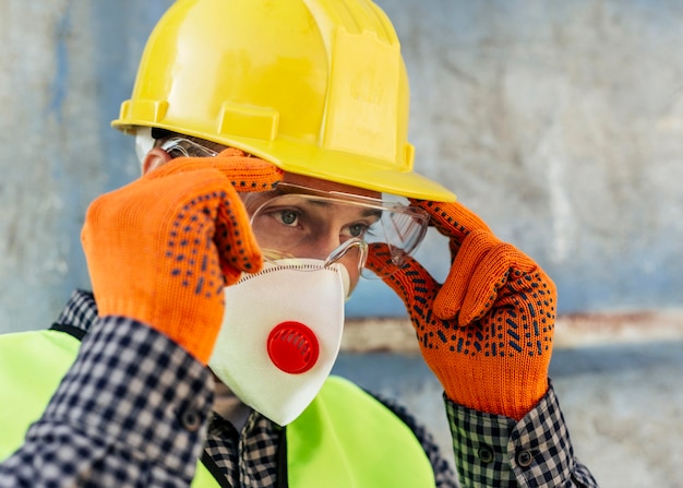 Фото Работник поправляет защитные очки в маске и перчатках