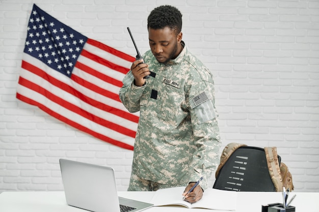 Worker of American army writing documents, using laptop.