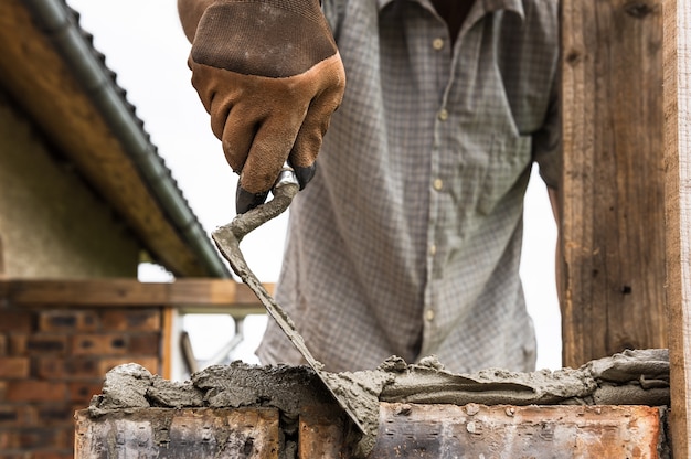 Worker applying a mortar with a trowel to the brick