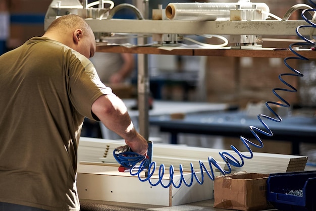Foto un operaio assembla mobili in una fabbrica. produzione industriale di mobili.