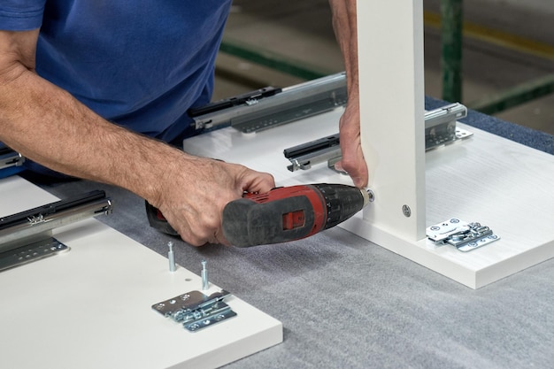 A worker assembles furniture at a factory. Industrial production of furniture.