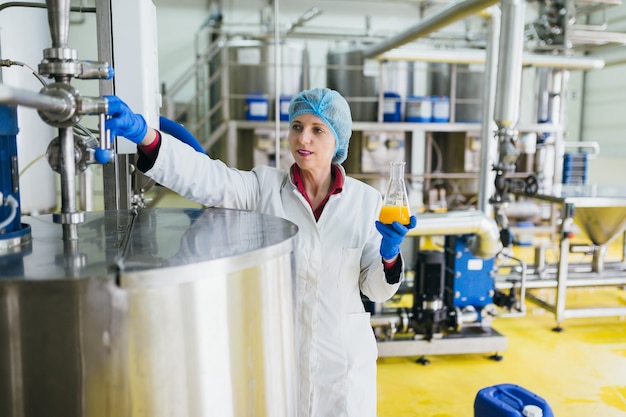 Worker at bottling factory checking juice quality.