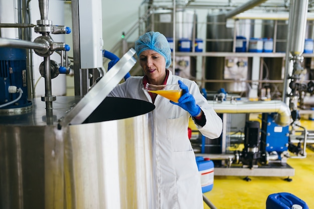 Worker at bottling factory checking juice quality.