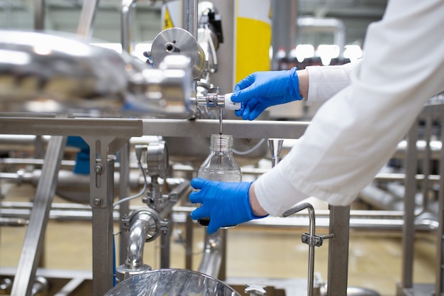 Photo worker at bottling factory checking juice quality