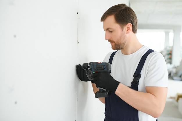 Worker builder installs plasterboard drywall at a construction