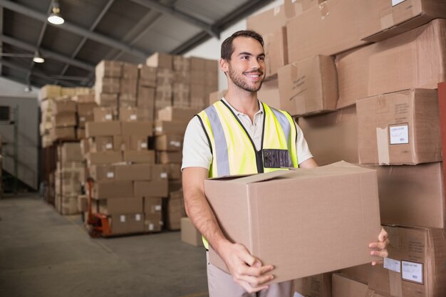 Worker carrying box in warehouse