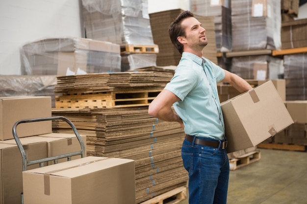 Worker carrying box in warehouse