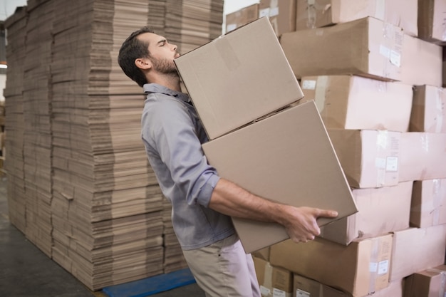 Worker carrying boxes in warehouse