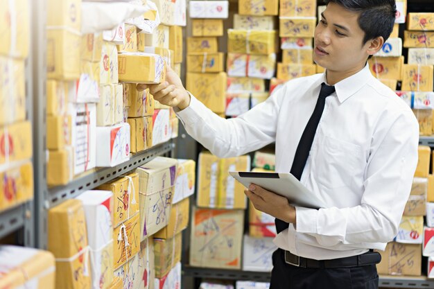 Worker checking package by using tablet in warehouse.