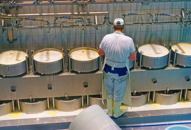 Worker of the cheese making factory of Gruyeres during industrial production of Gruyere cheese