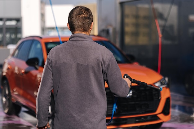 Worker cleaning car using high pressure water self servise car washing clean auto