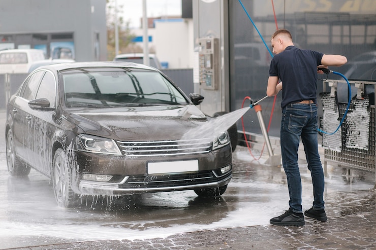 高圧水を使用して車を掃除する労働者。